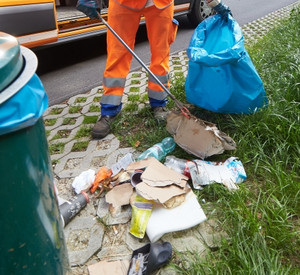 Mitarbeiter sammelt wilden Müll an Parkplatz